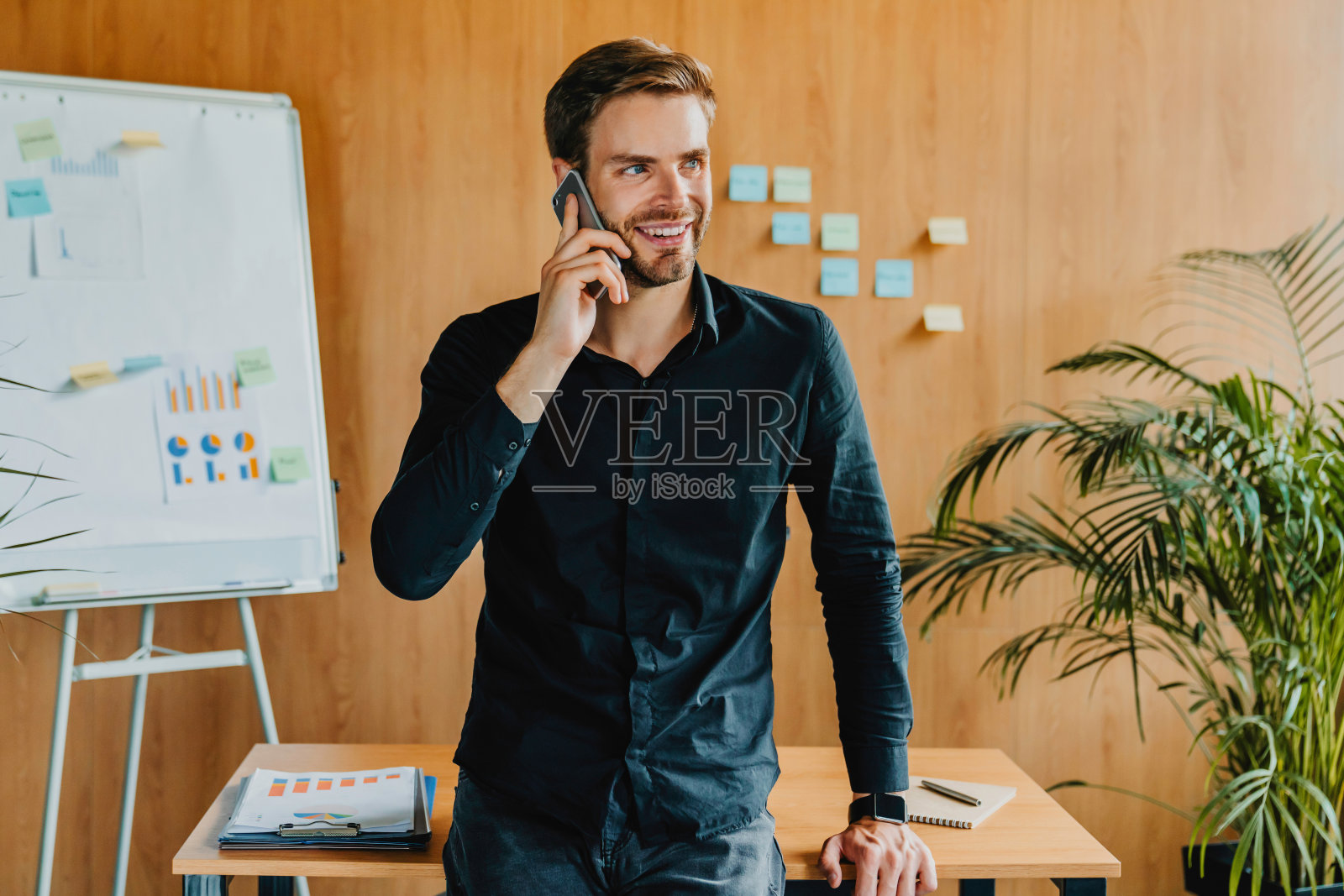 男性白人经理在办公室站在办公桌附近打电话照片摄影图片