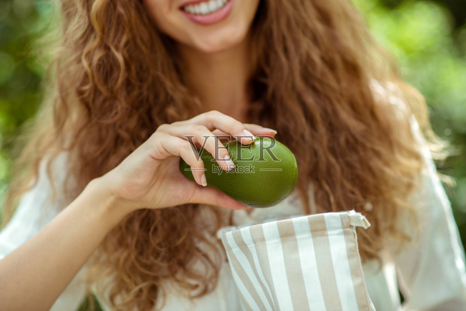 穿白衬衫的女人把牛油果放进袋子里照片摄影图片