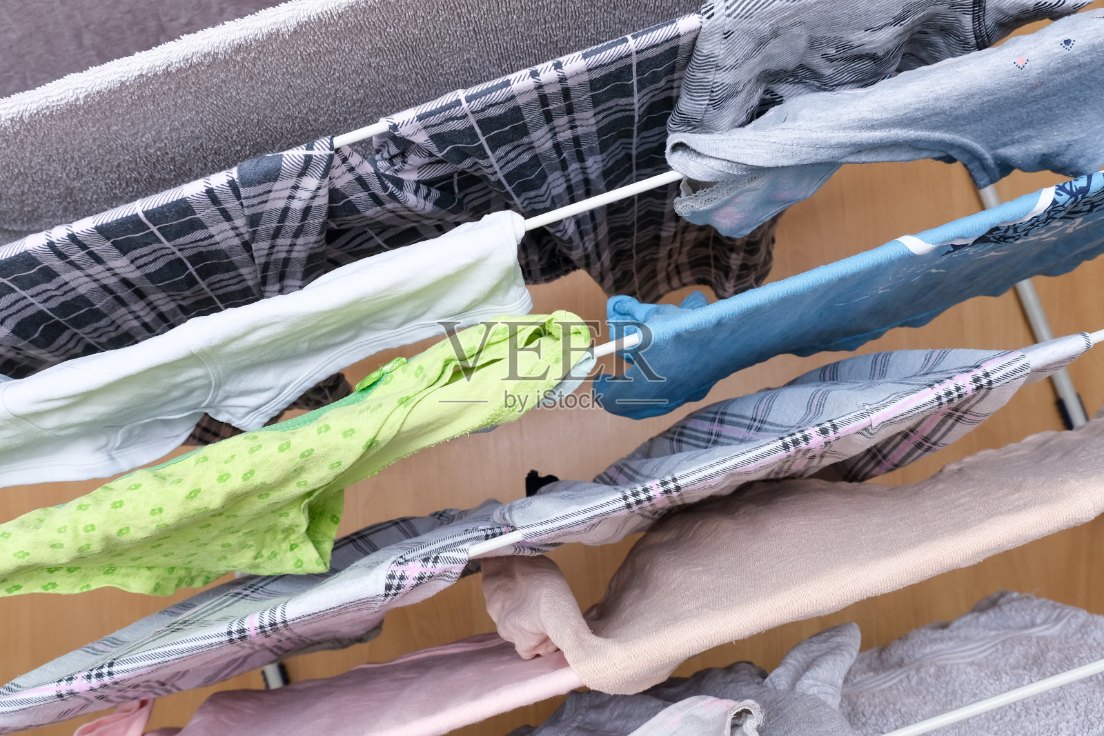 新鲜洗过的亚麻布，衣服挂在烘干机上，干燥的衣服在折叠便携式烘干机近，家务，家庭作业和家务概念照片摄影图片