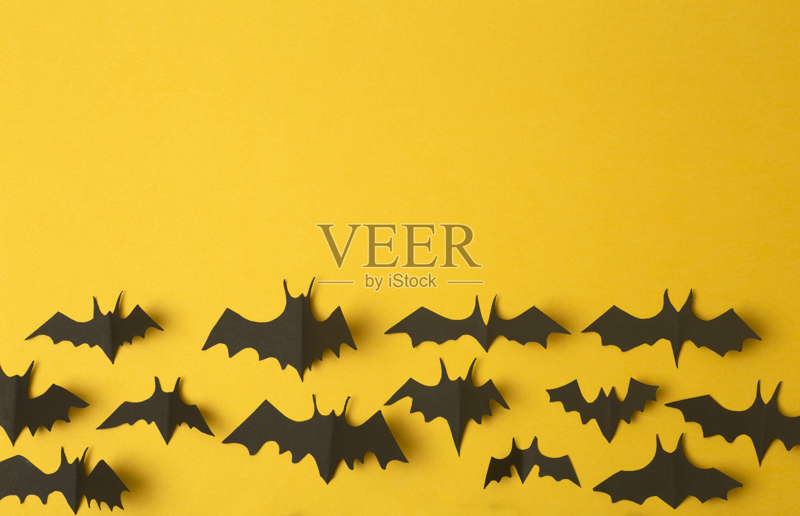 万圣节的背景。黑色蝙蝠在黄色背景的纸上剪下来。万圣节装饰和节日装饰，拷贝空间。照片摄影图片