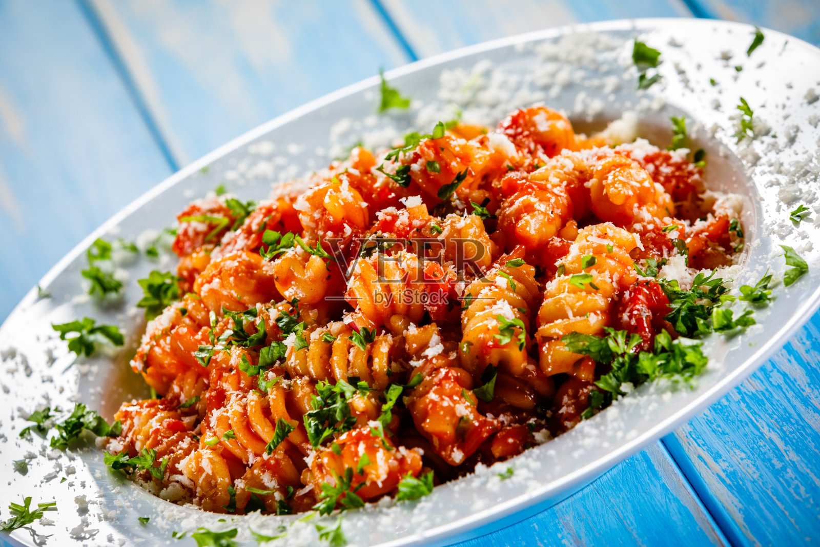 木桌上的意大利面配番茄酱、猪肉和帕尔马干酪照片摄影图片