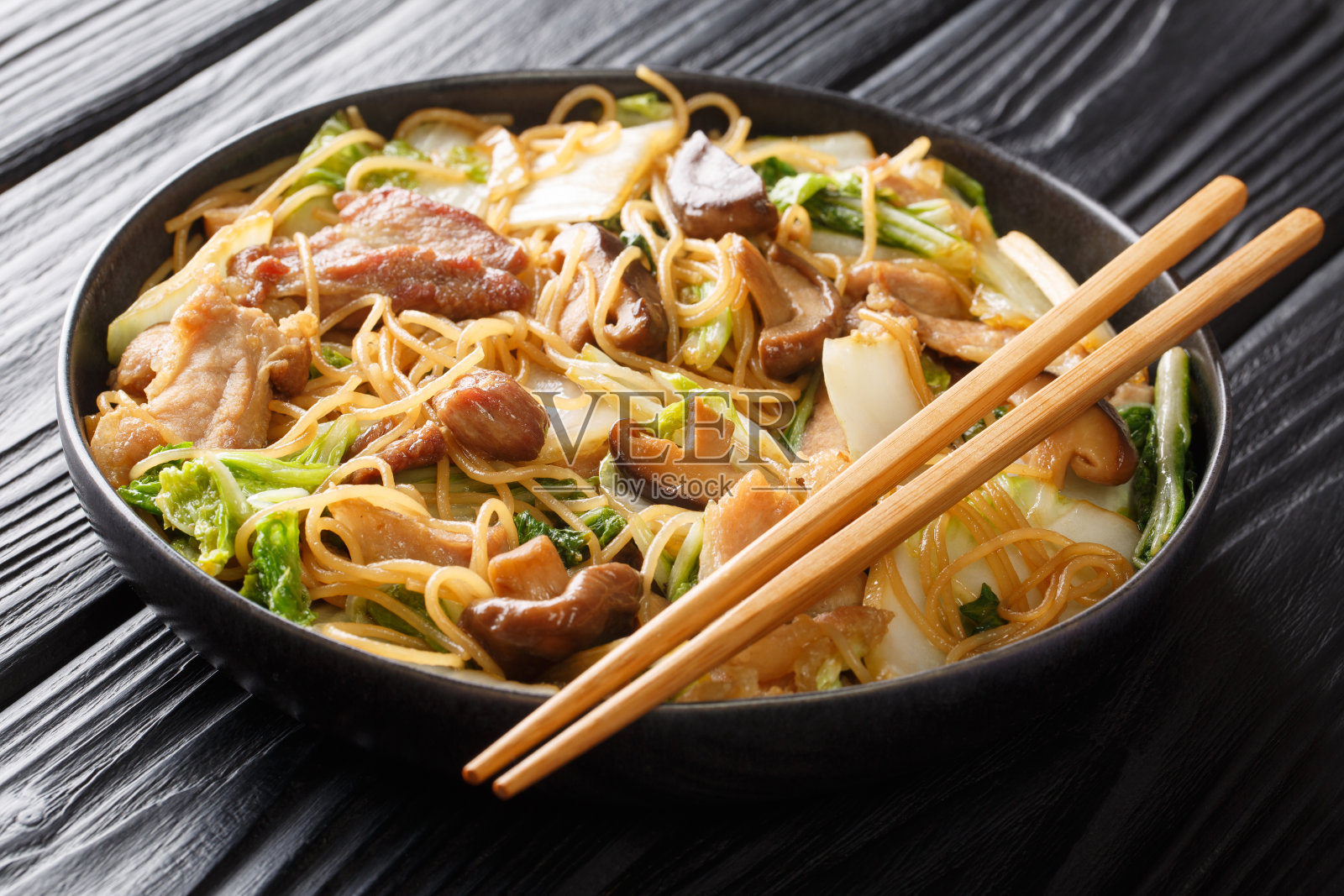 玻璃纸面条与五花肉，蘑菇和白菜一起煮在盘子里。水平照片摄影图片