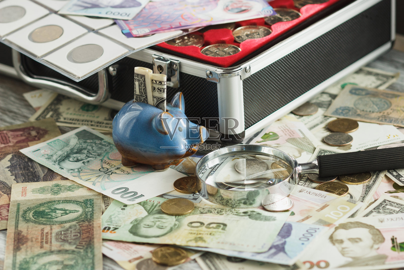 不同的硬币和纸币配有放大镜和储蓄罐照片摄影图片