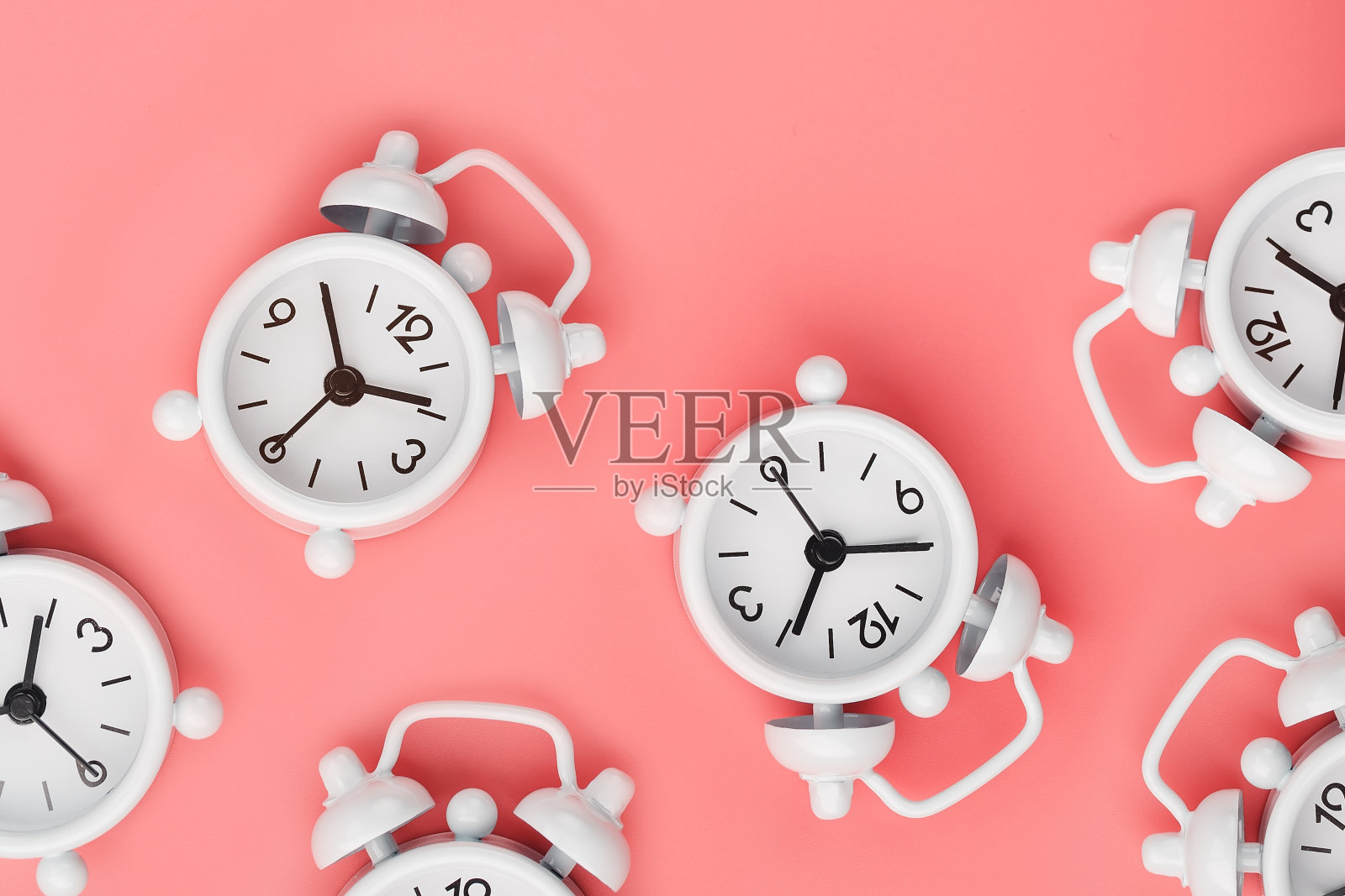 以粉红色为背景的许多白色经典闹钟的图案。用顶视图复制空间，平铺。照片摄影图片