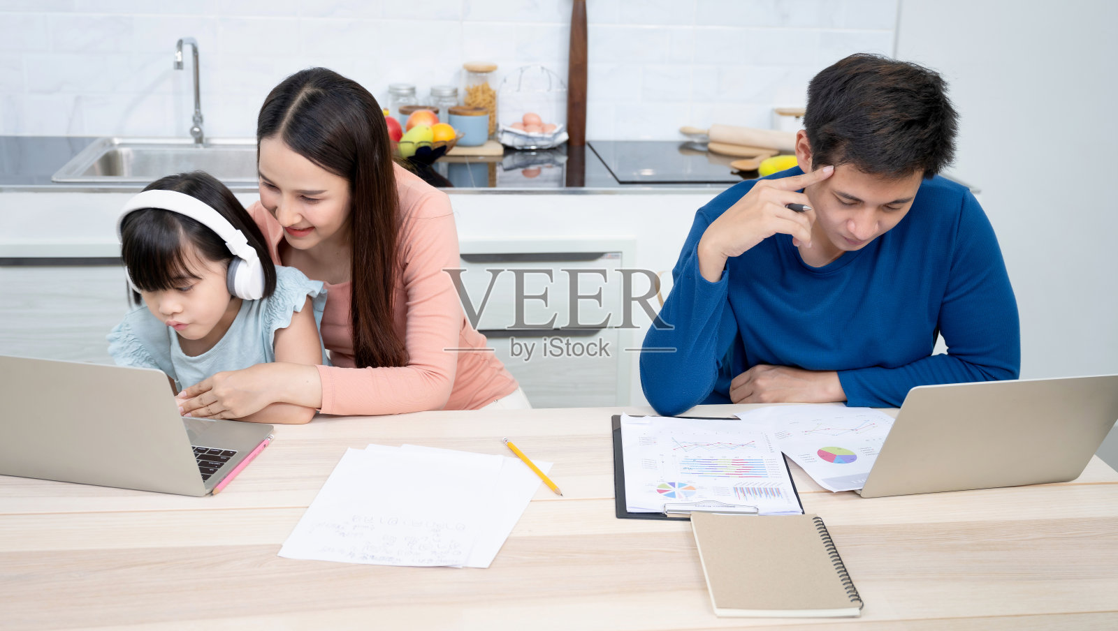 小女孩在妈妈的帮助下写书，而爸爸在家里工作压力很大照片摄影图片