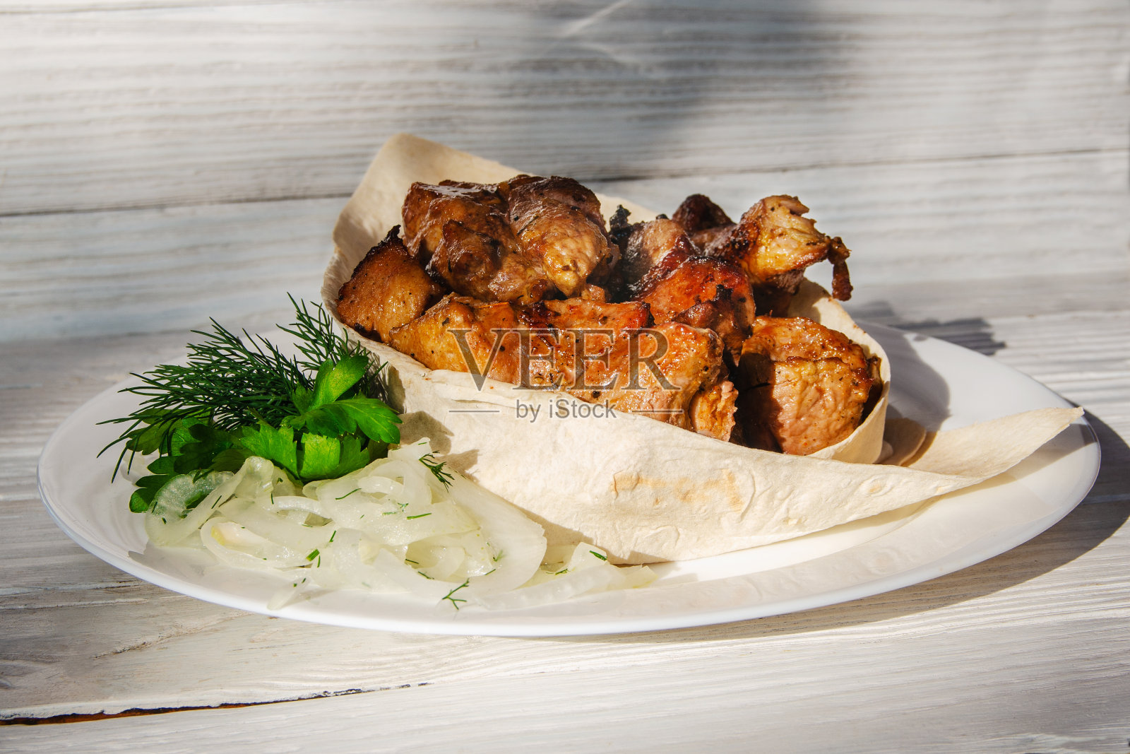 烤好的肉放在皮塔饼里，配上香草和新鲜的洋葱。照片摄影图片