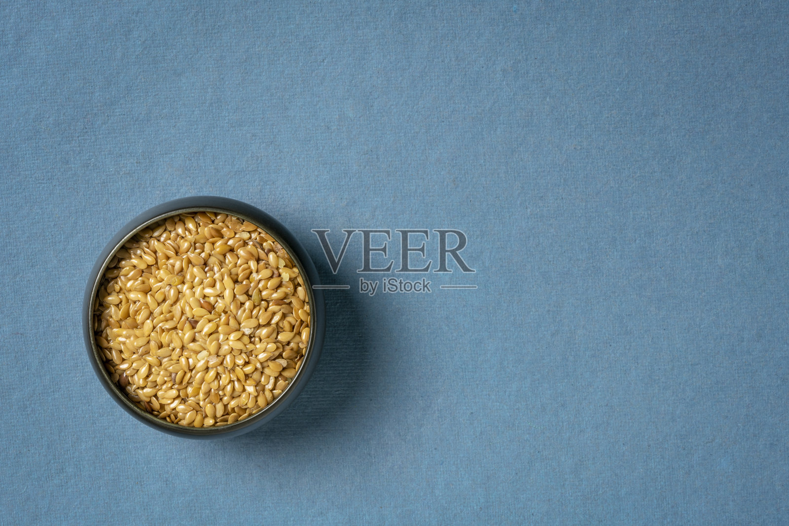 金色的亚麻籽放在一个小陶瓷碗里照片摄影图片