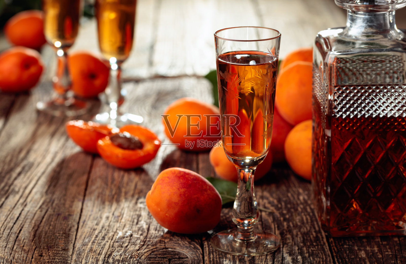 自制的杏子酒或格拉巴酒和新鲜的杏子放在旧木桌上。照片摄影图片