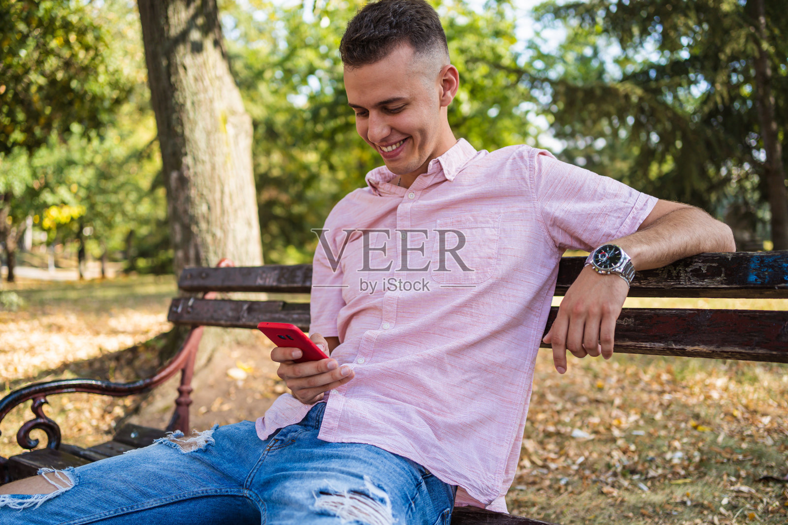 一名男子在公园长凳上玩手机照片摄影图片