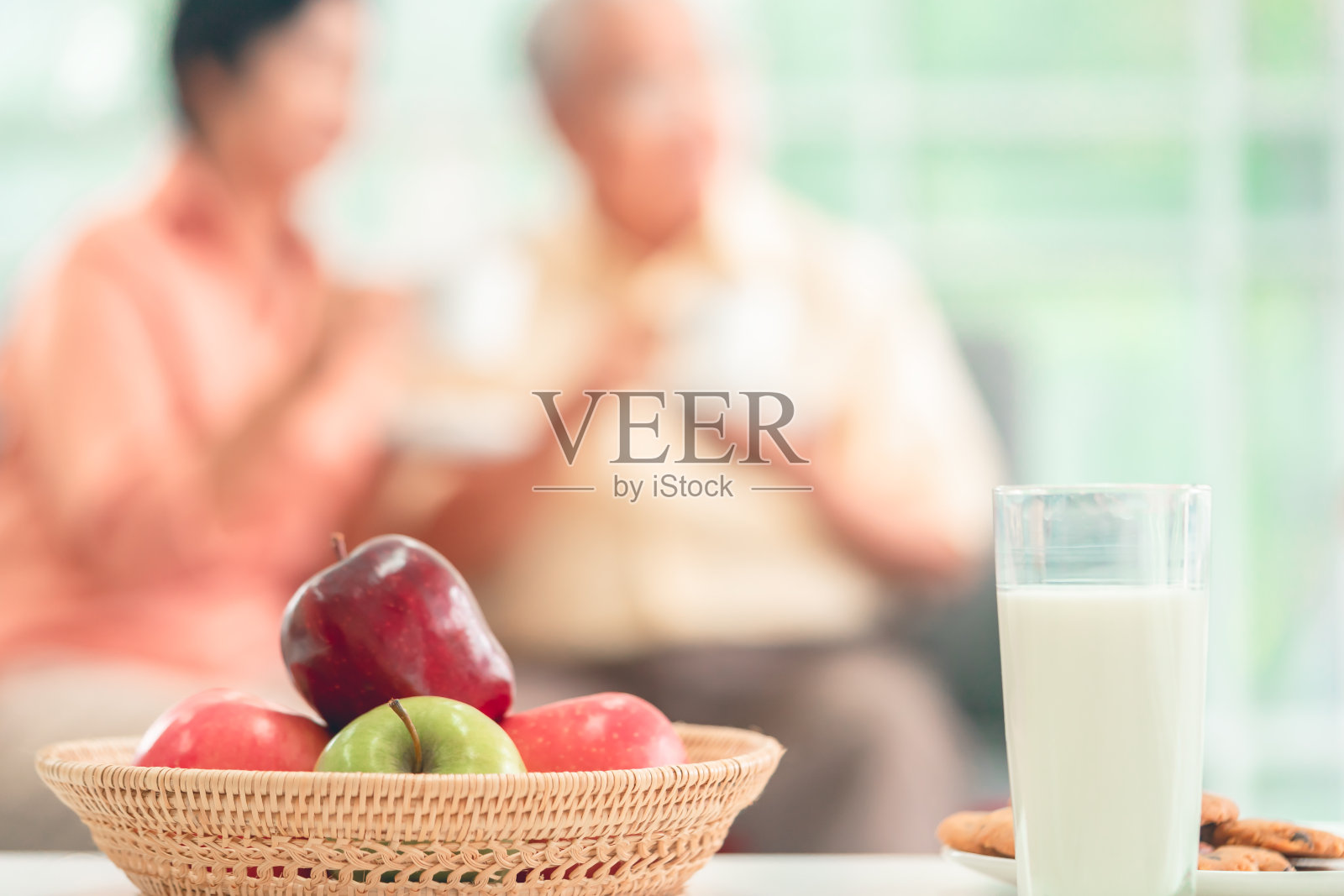 水果饼干和牛奶早餐与老年夫妇为背景，以健康的老年人生活方式。照片摄影图片