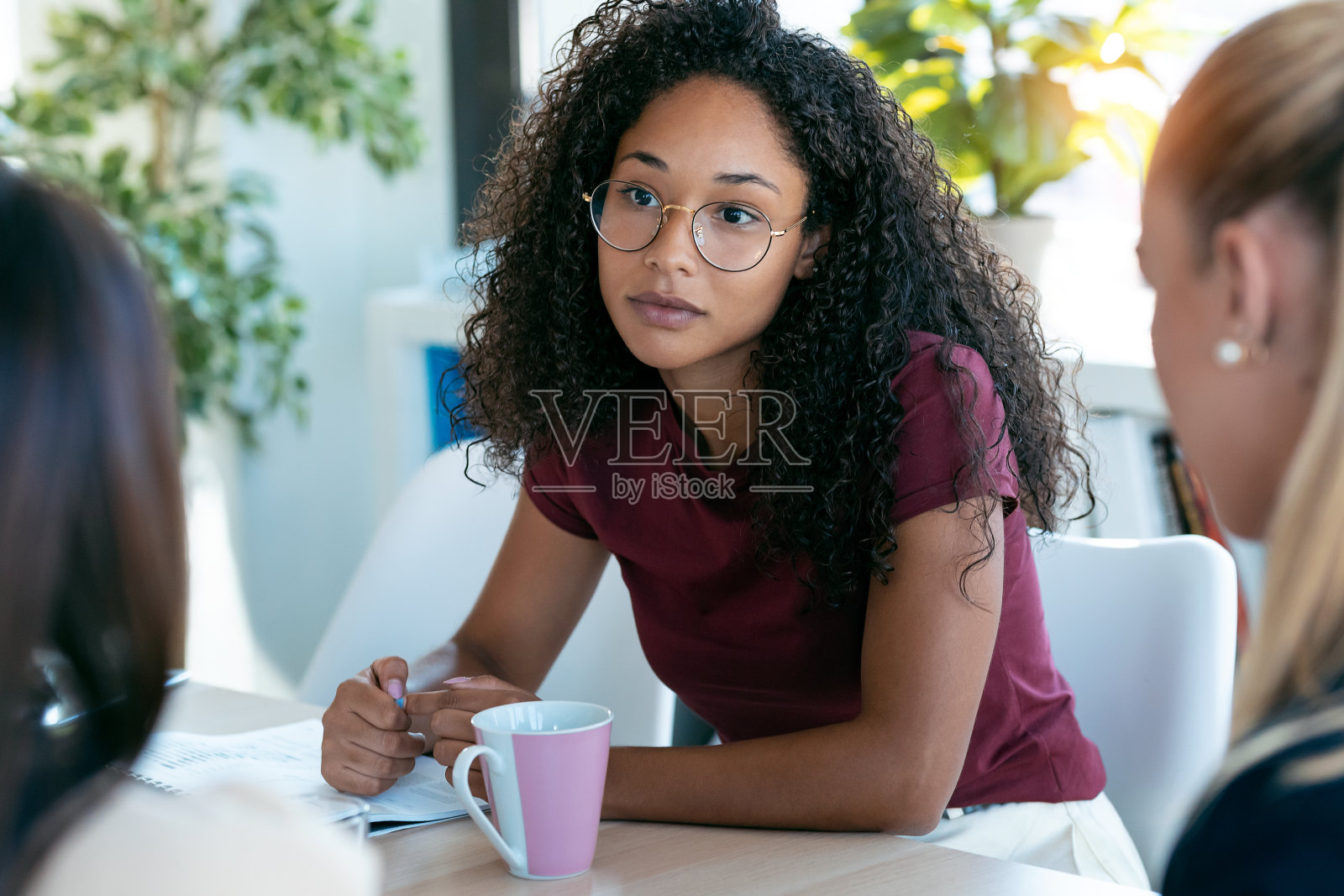 自信的非洲年轻女商人倾听她的合作伙伴，同时工作在共同的工作空间。照片摄影图片