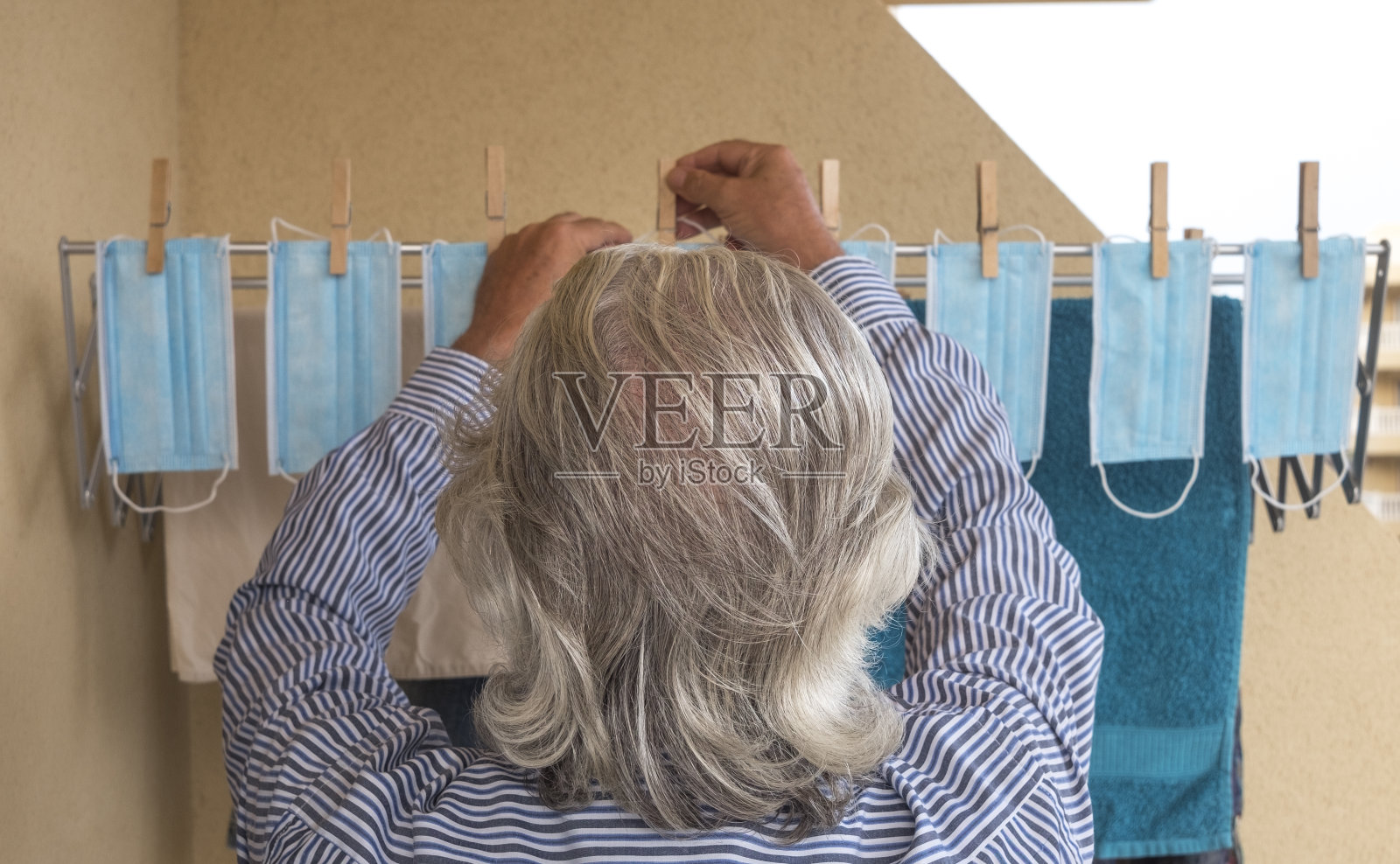 后视图一位老人挂在晾衣绳上的防护口罩——防covid-19等病毒感染的口罩——大家庭照片摄影图片