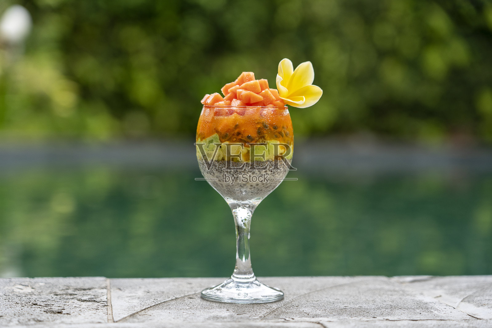 奇亚种子布丁，木瓜，百香果，芒果和鳄梨在一个玻璃杯的早餐背景游泳池的水，特写。健康饮食的概念，超级食物照片摄影图片