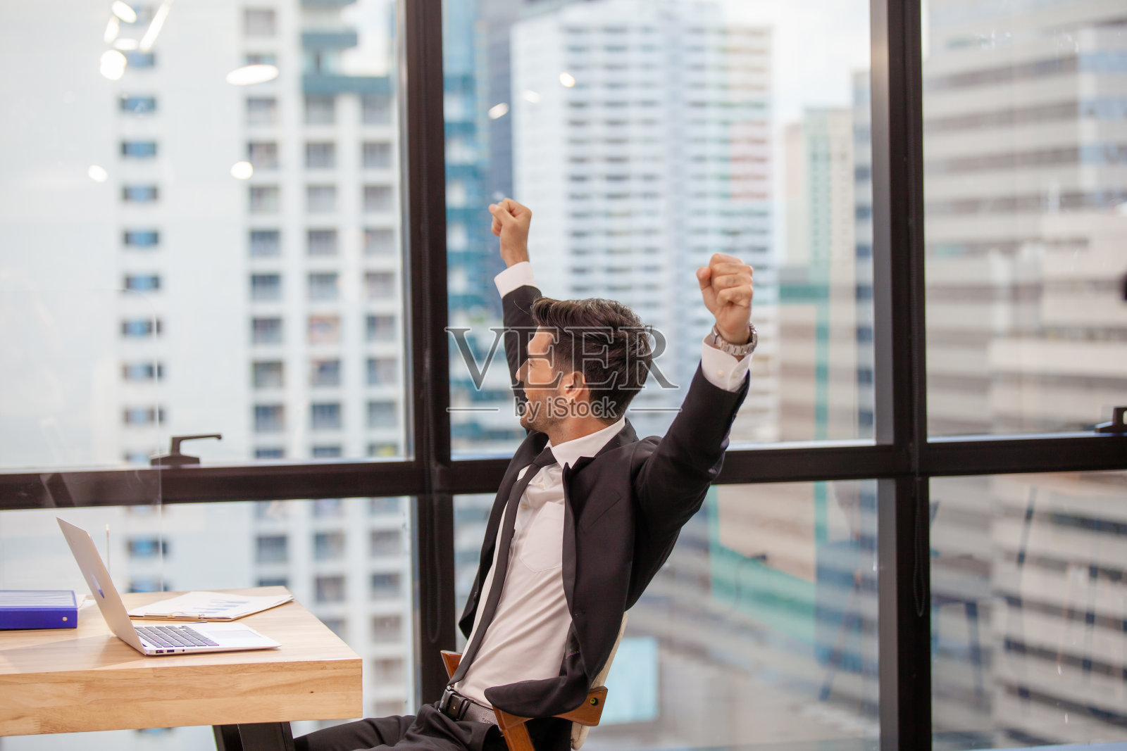 商人庆祝他的成功。胜利者，成功的商人举起手臂庆祝他的胜利照片摄影图片