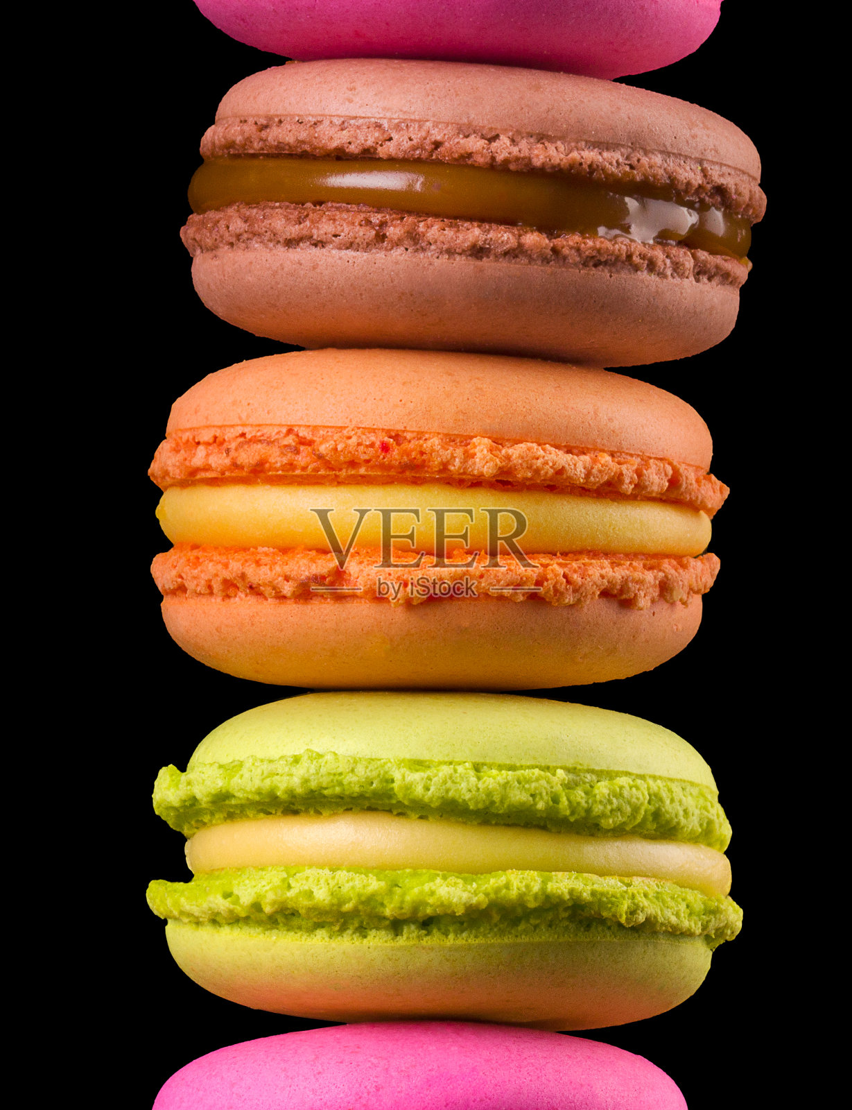 一堆法国彩色杏仁饼放在木桌上，孤立在黑色背景上照片摄影图片