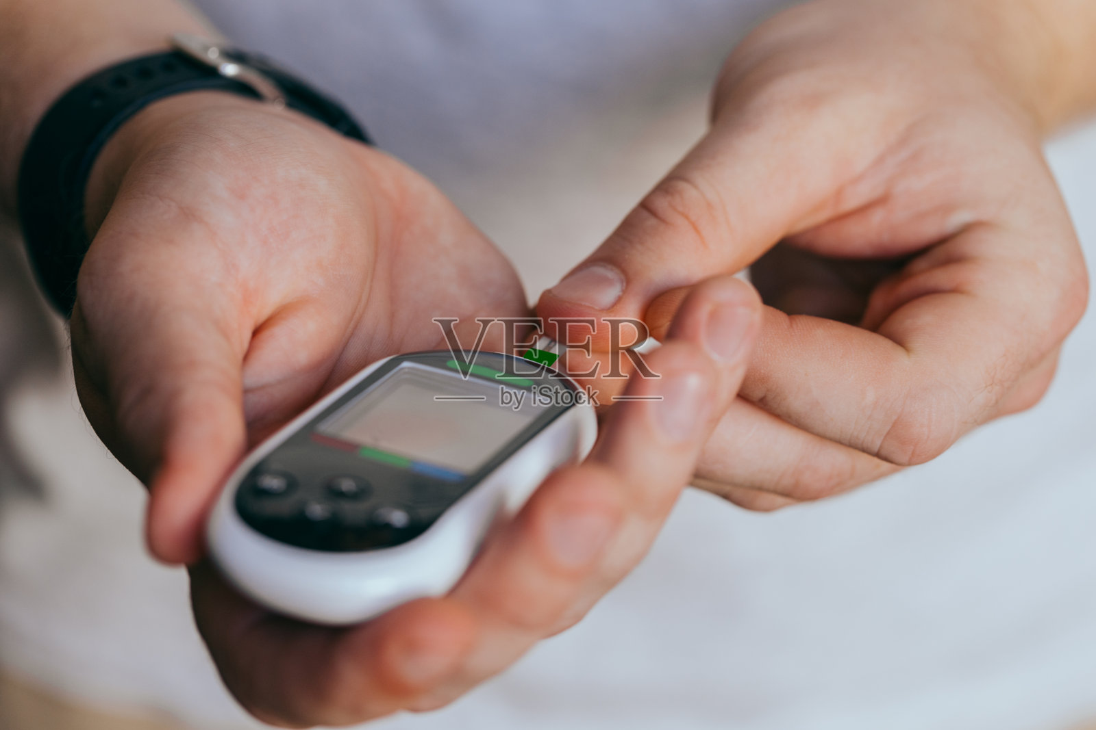 糖尿病，医疗保健-特写的一个男人与一个血糖仪和测试条检查血糖在家照片摄影图片