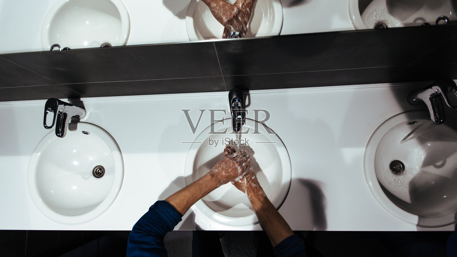 前视图。一个男人在浴室里仔细地洗手照片摄影图片