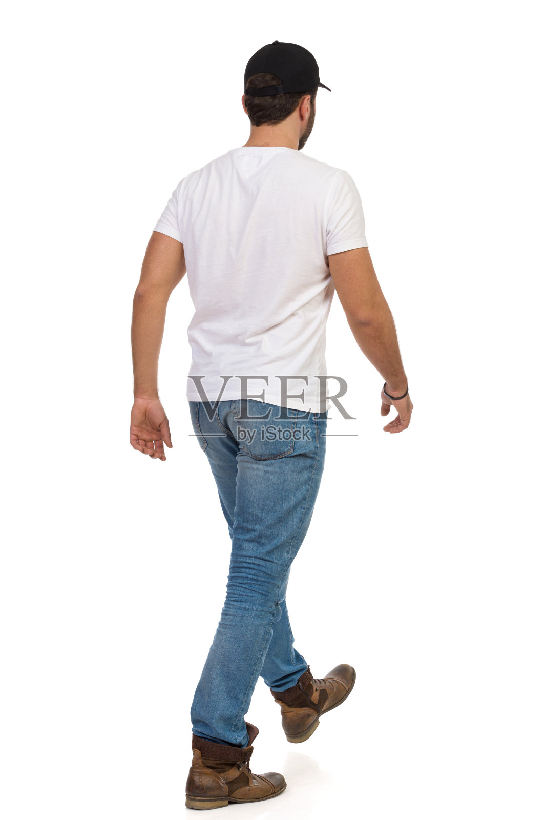 后视图行走的人在靴子，牛仔裤，白色t恤和黑色帽子。照片摄影图片