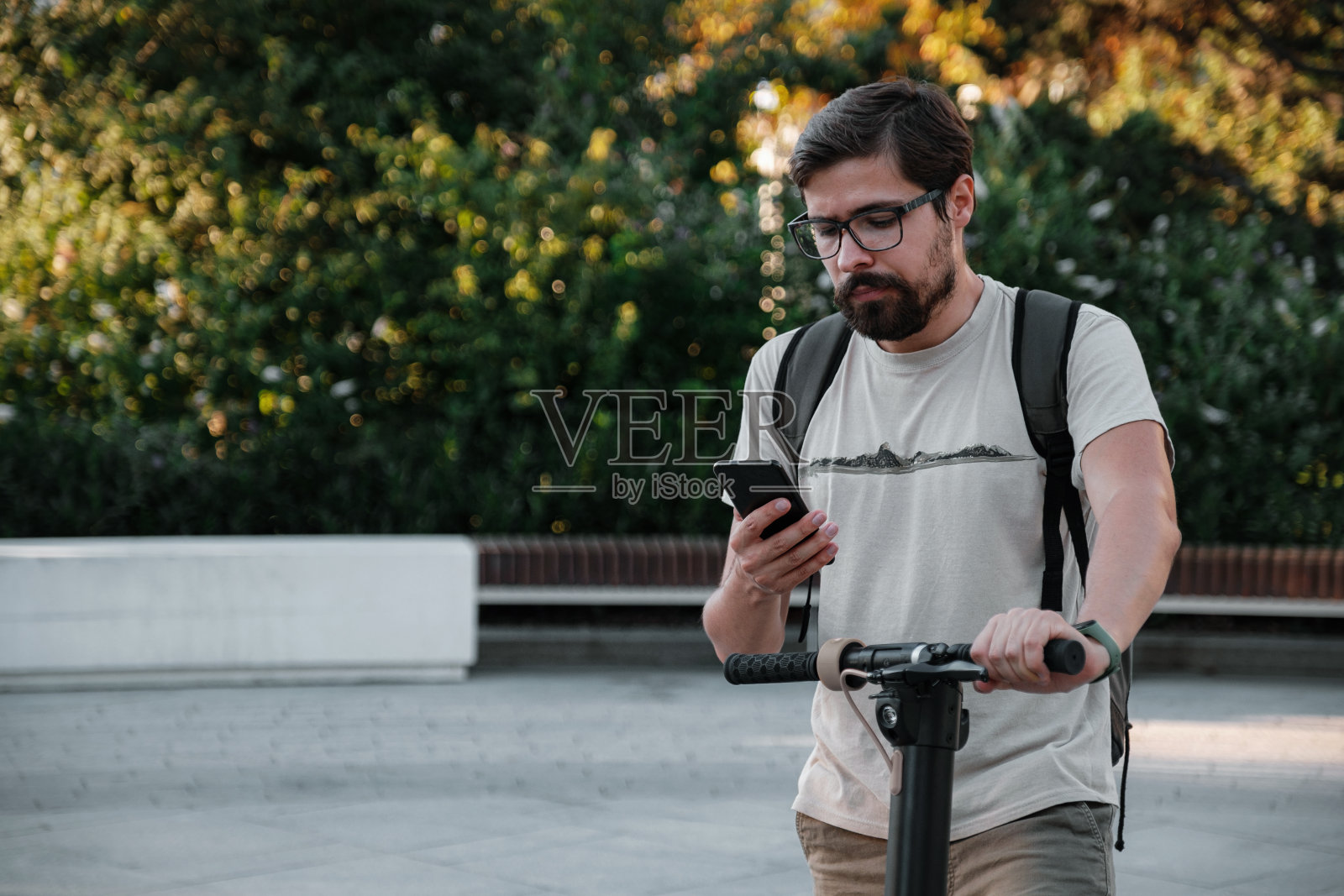 用智能手机在城市里骑着电动滑板车上下班的潮人照片摄影图片