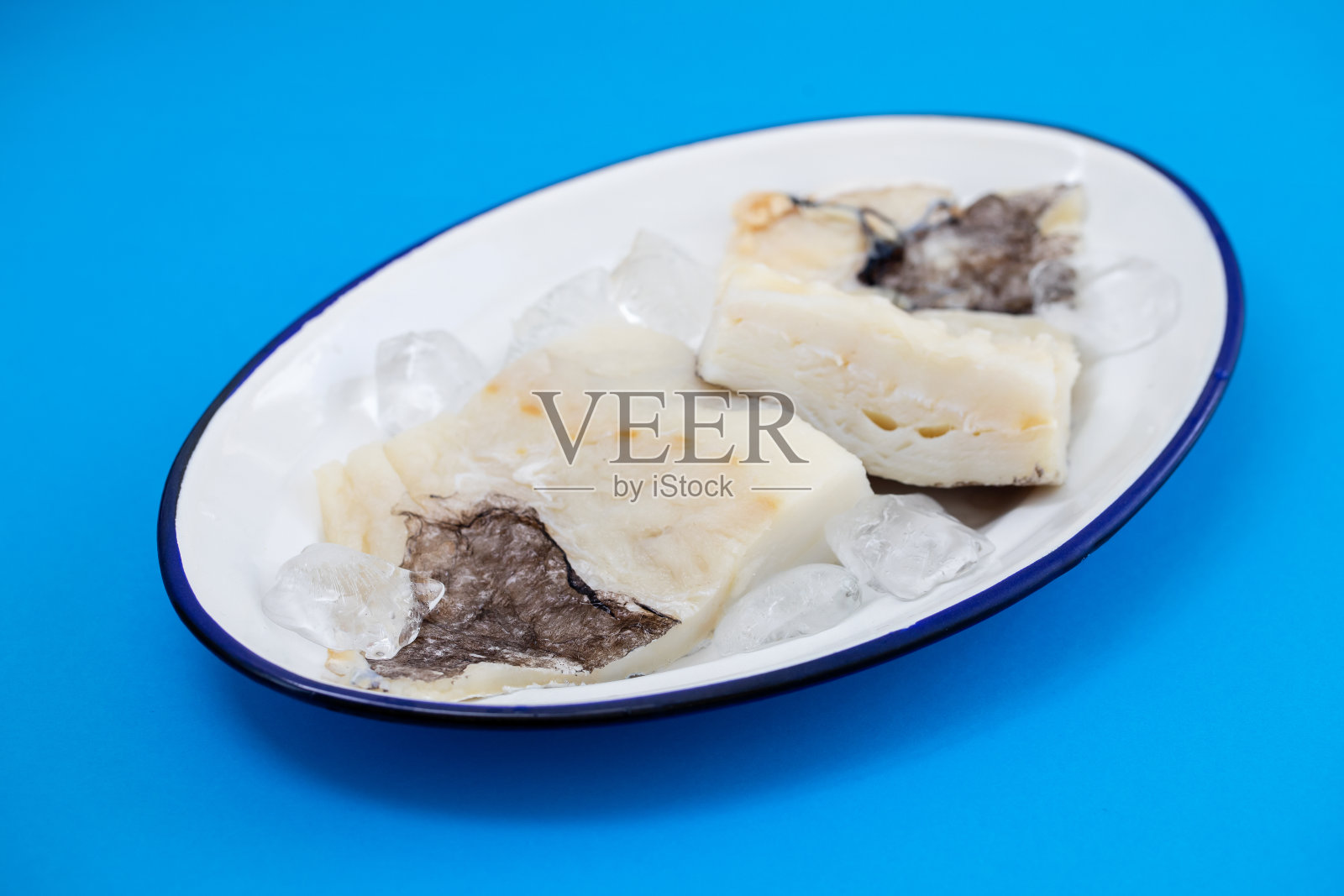 新鲜的生鳕鱼与冰盘上的陶瓷背景照片摄影图片