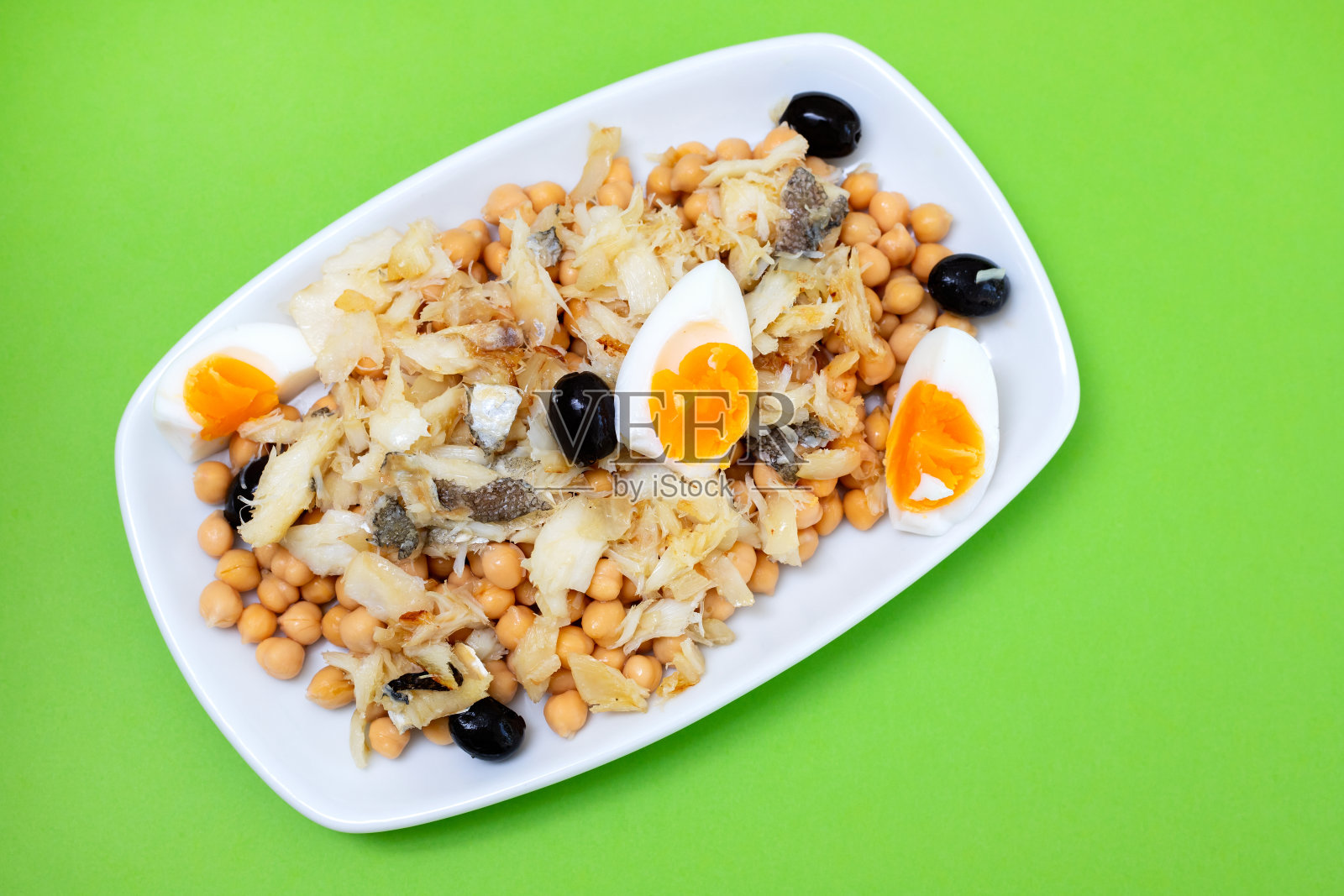 鹰嘴豆配鳕鱼、橄榄和煮鸡蛋，以陶瓷为背景照片摄影图片