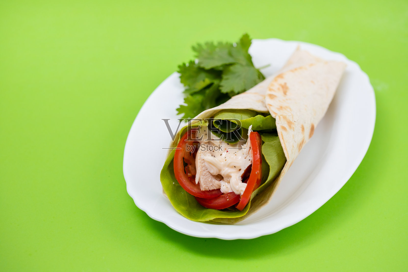 鸡肉和沙拉玉米饼卷在白色的盘子上，在绿色的背景照片摄影图片