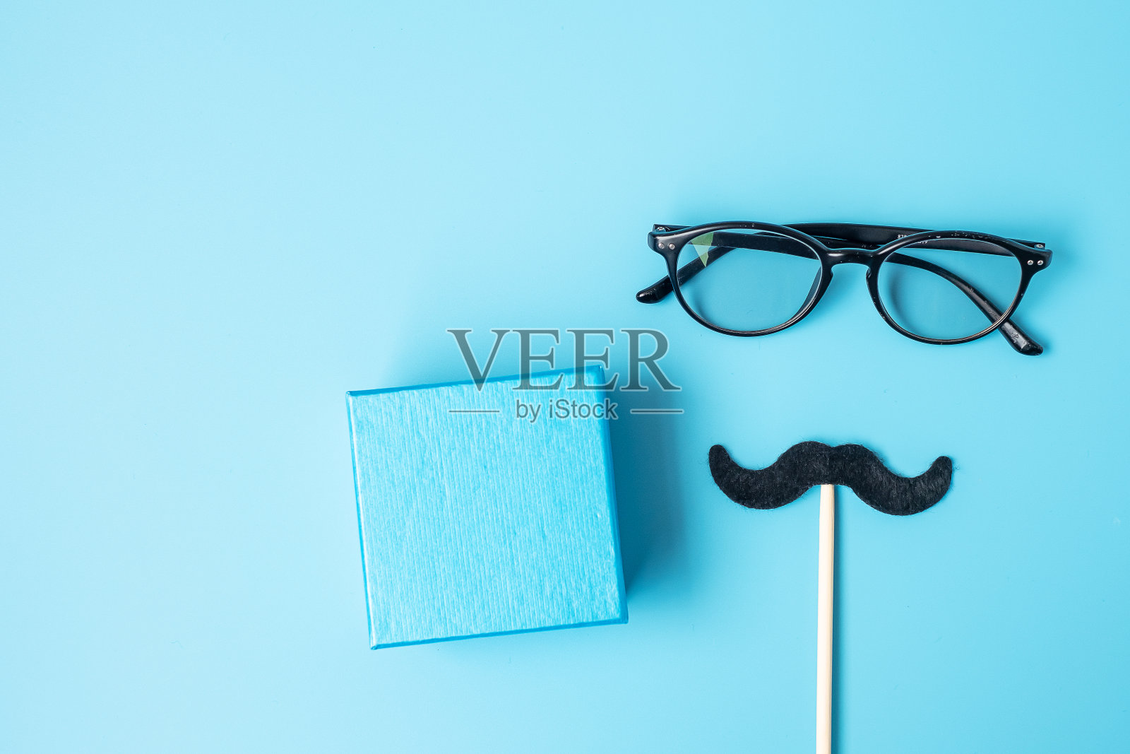 最小的黑色胡子，礼物和眼镜在蓝色背景。父亲节和国际男人节概念快乐照片摄影图片