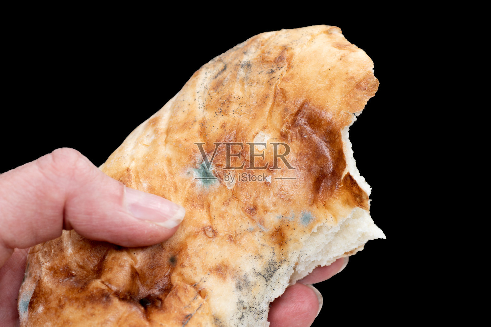 女性手里拿着一块霉烂的旧面包孤立在黑色背景上，特写，选择性聚焦照片摄影图片