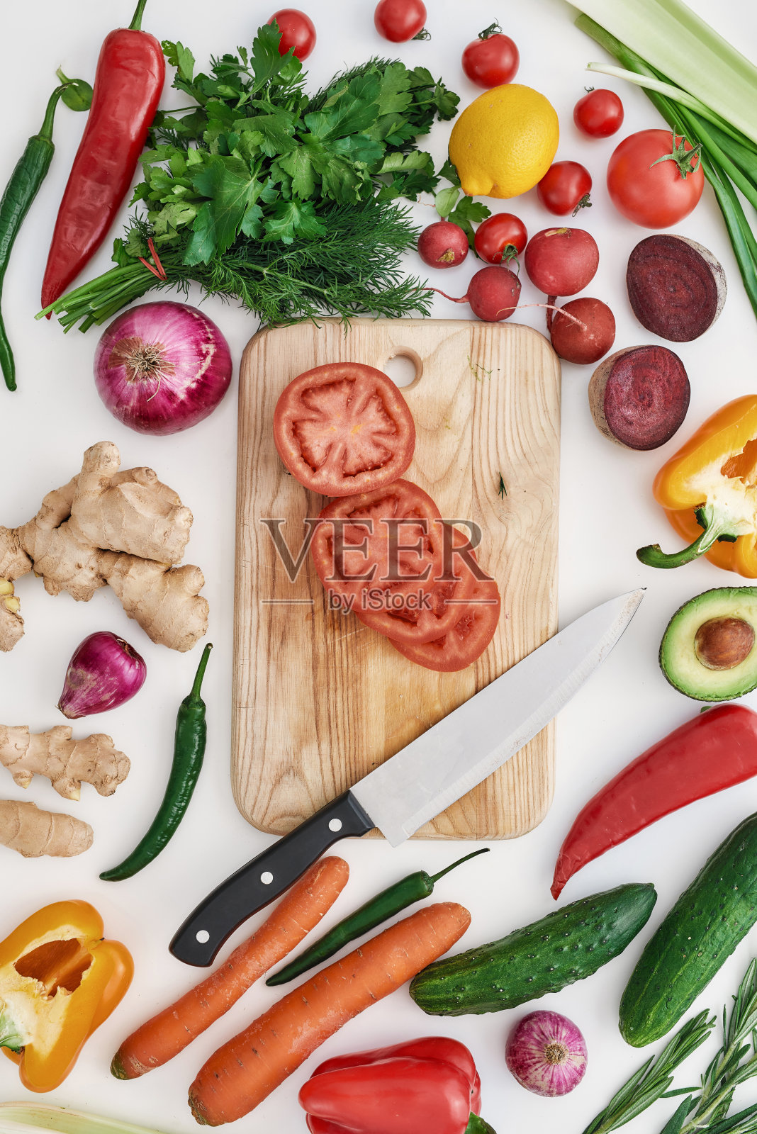 俯视图各种彩色蔬菜和香草制作夏季沙拉，切片的番茄和刀切板孤立在白色背景照片摄影图片