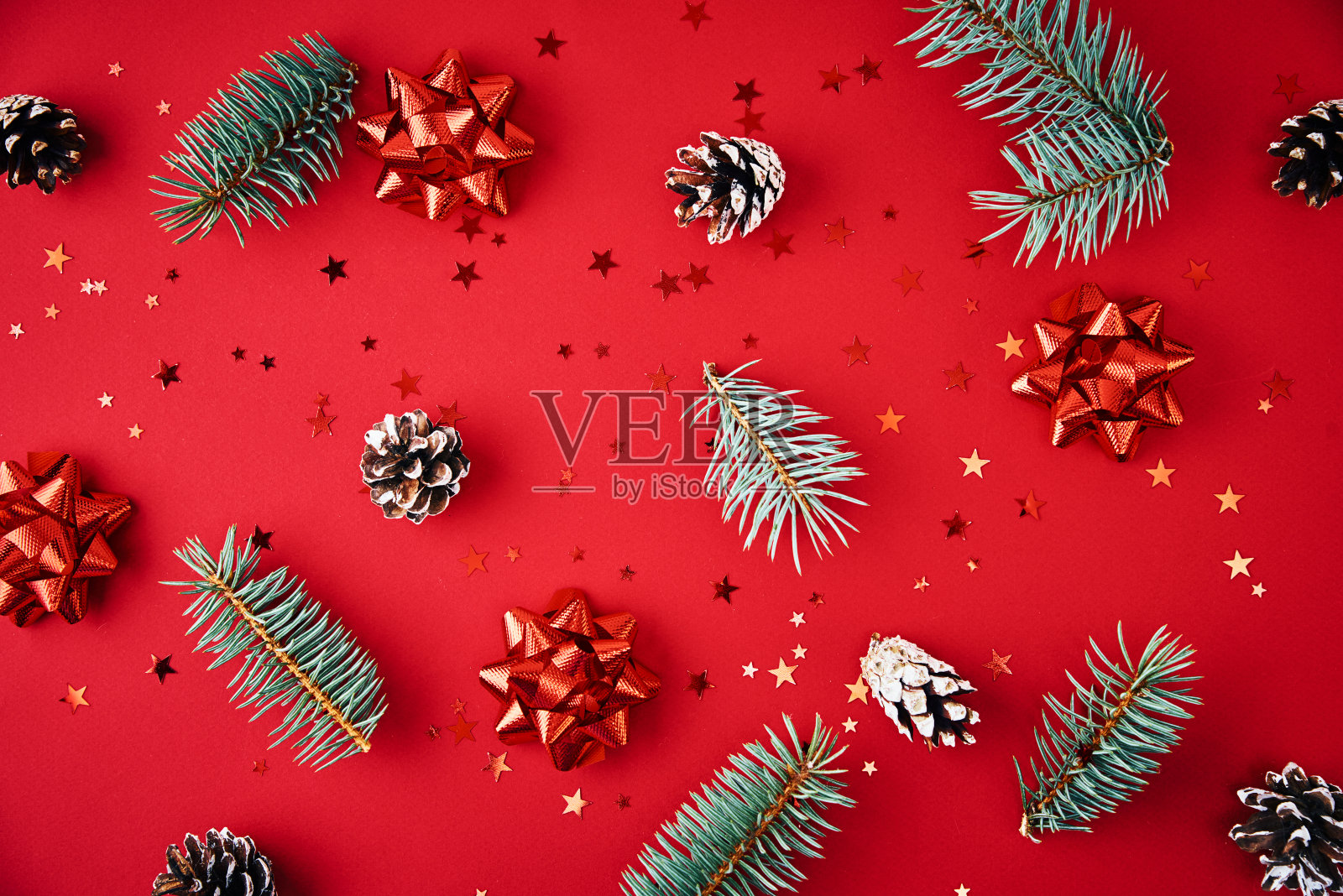 圣诞组成。冷杉枝，松果和节日的五彩纸屑在红色的背景，俯视图照片摄影图片