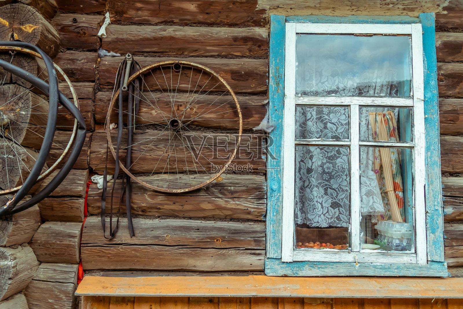 自行车轮子挂在一个旧木屋的墙上有一个旧窗户照片摄影图片