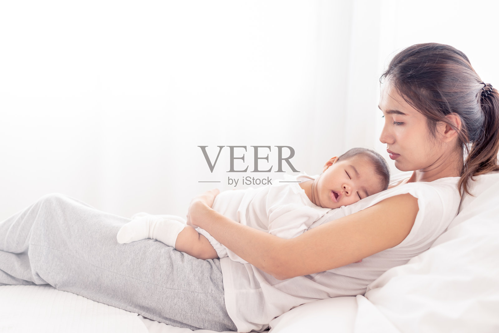 做妈妈太累了。晚上，疲惫的母亲抱着刚出生的婴儿躺在床上。真实真实的生活疲惫的父母与新生儿休息。照片摄影图片