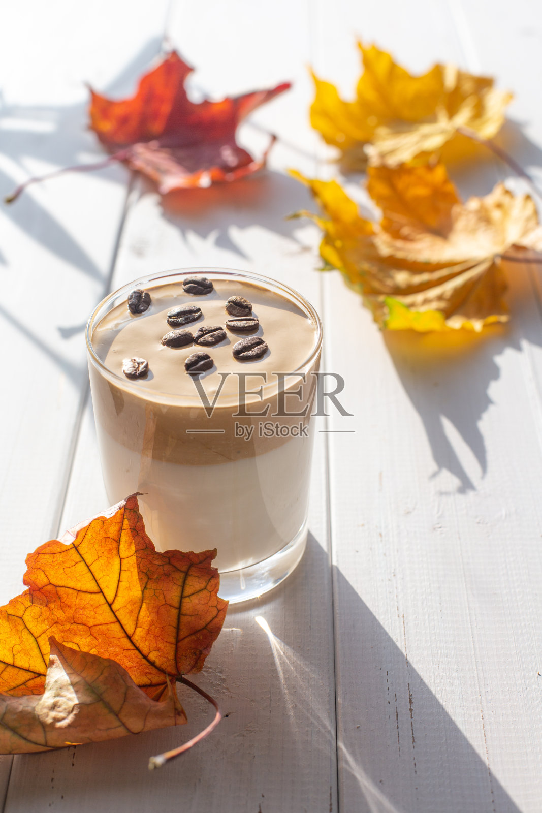 传统的韩国含咖啡因的牛奶饮料，Dalgona咖啡在一个玻璃杯和咖啡豆在白板的背景。照片摄影图片