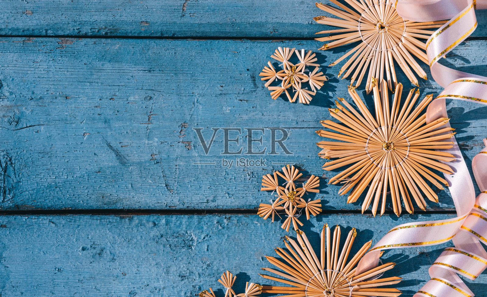 木制圣诞背景，俯视图。放置文字在新年的背景。美丽的蓝色圣诞背景草雪花和粉红色的丝带。照片摄影图片