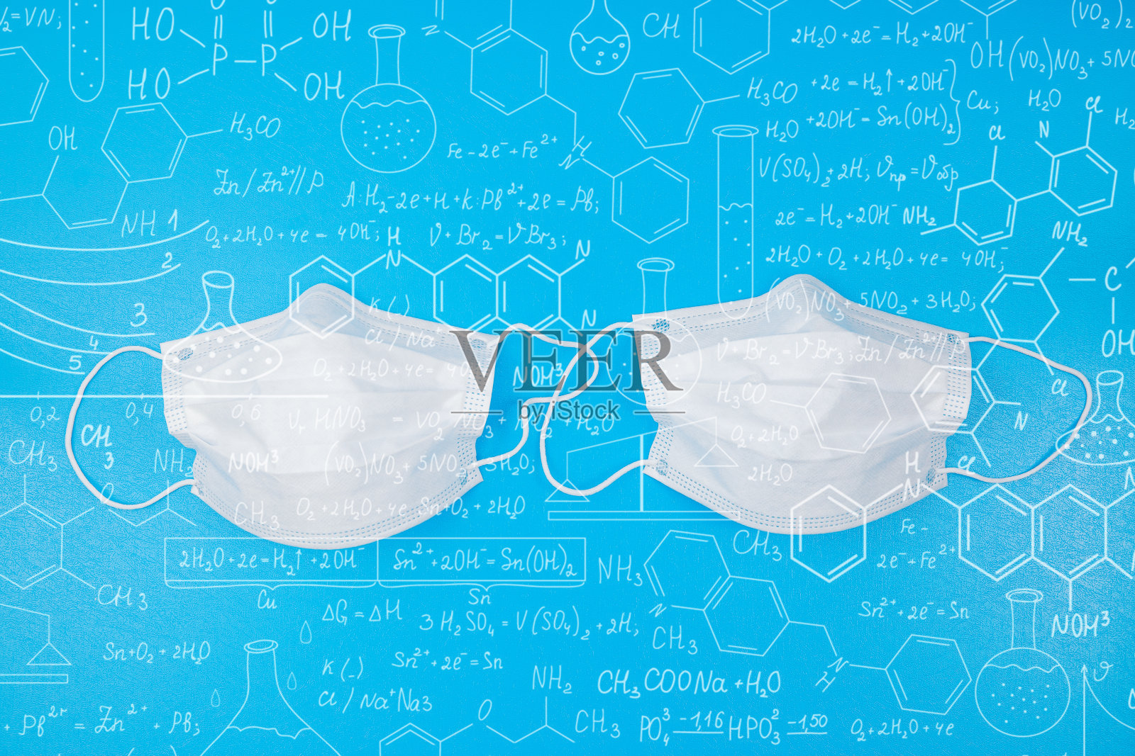 抗击冠状病毒概念:蓝色背景下，被COVID-19病毒包围的蓝色外科防护口罩。照片摄影图片