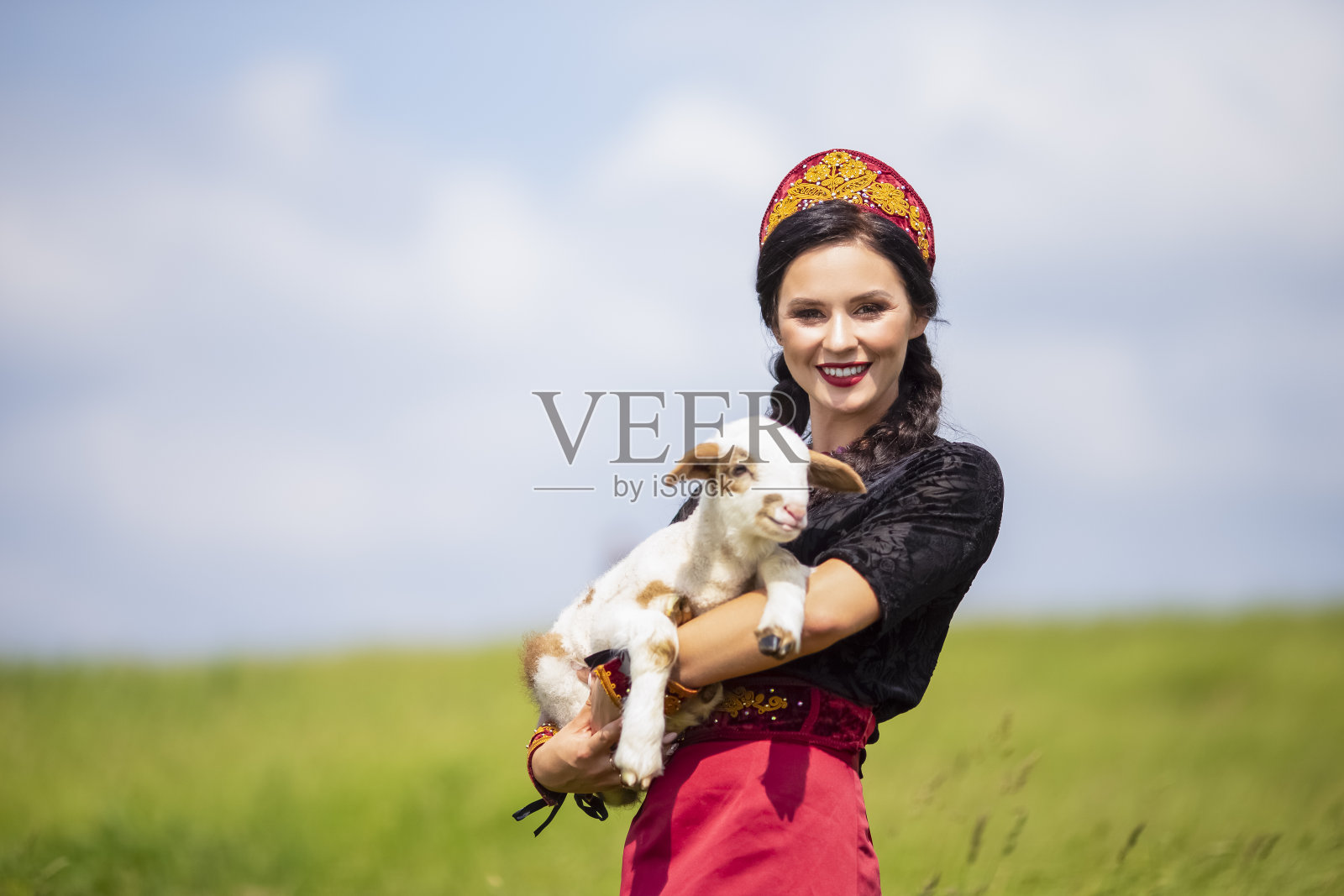 魅力白种人模特在俄罗斯风格的科科史尼克与新生的小羊羔在自然背景下摆姿势。水平图像组成照片摄影图片