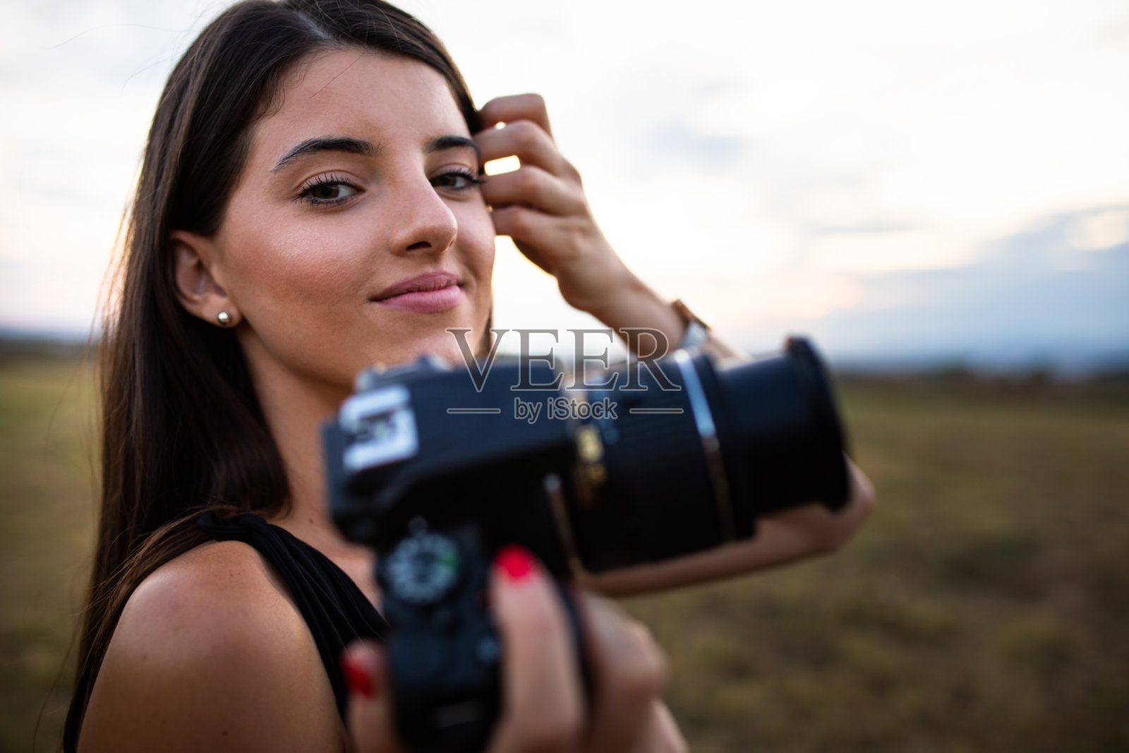 一个漂亮的年轻女人拿着相机微笑着照片摄影图片
