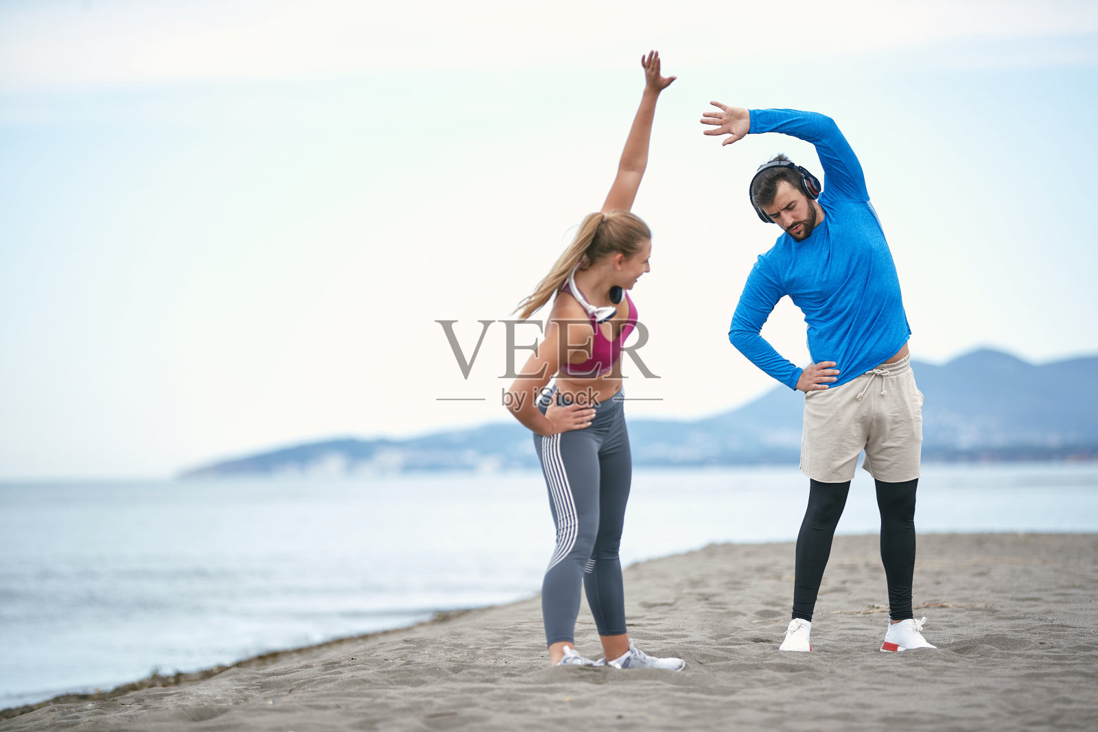 一对情侣在海滩上热身训练照片摄影图片