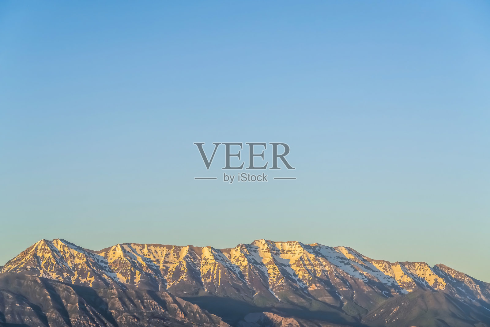 险峻的山峰覆盖着皑皑白雪，映衬着广阔的蓝天照片摄影图片