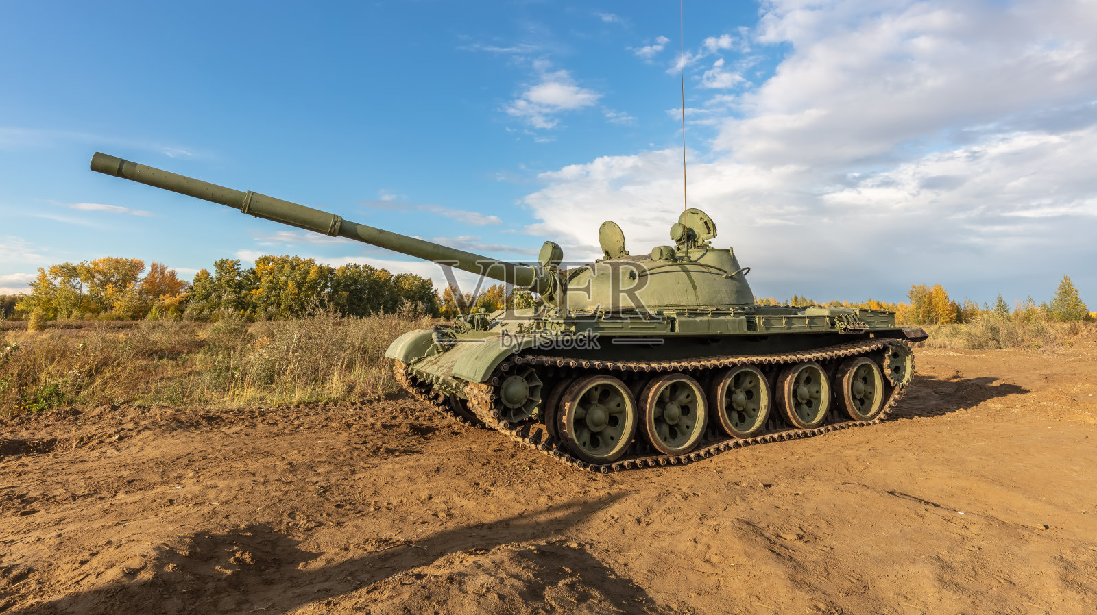 俄罗斯T-62坦克在战场上的侧面镜头。蓝色多云的天空作为背景。照片摄影图片