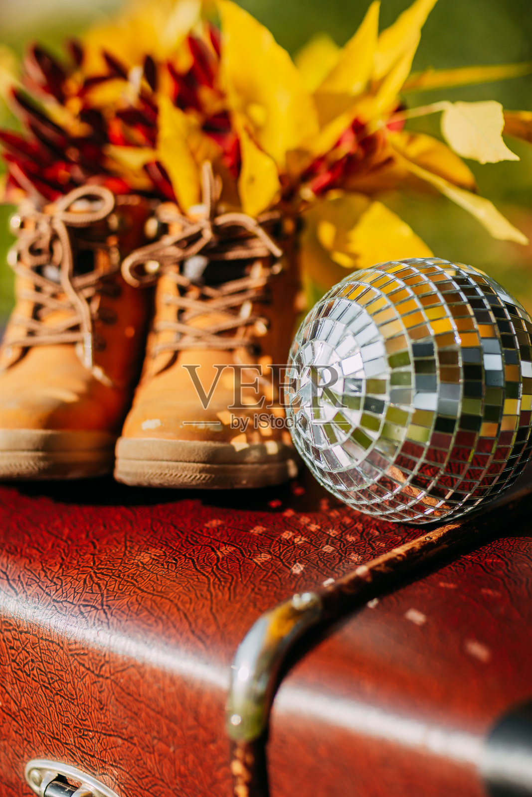 秋天森林里老式行李箱上的旧棕色靴子和迪斯科球。鞋子和树叶。秋天舒适，黄叶红叶。照片摄影图片