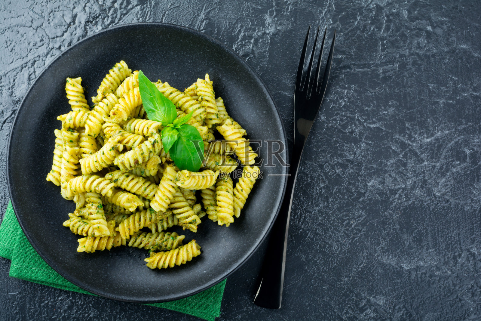 黑色背景的绿牛油果罗勒酱意大利面。有选择性的重点。前视图。副本的空间。照片摄影图片