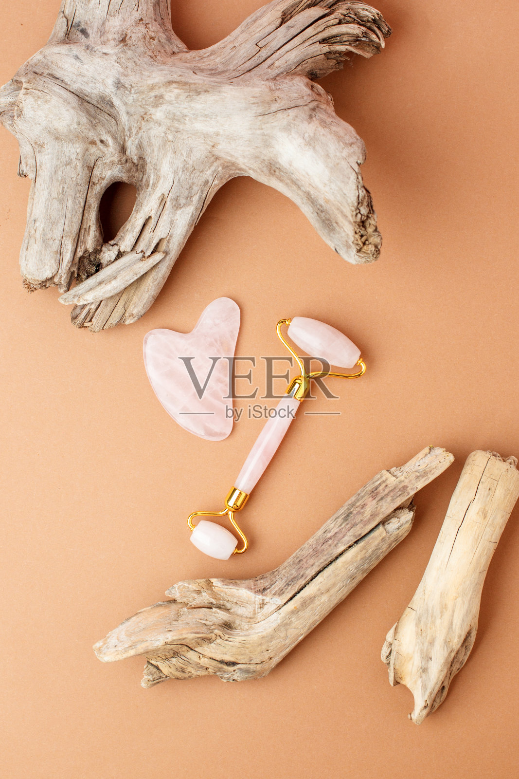 玉面滚轮和石美容面部按摩治疗。平铺米色背景与木本植物根-现代，时尚创意静物卡，时尚豪华养生概念照片摄影图片