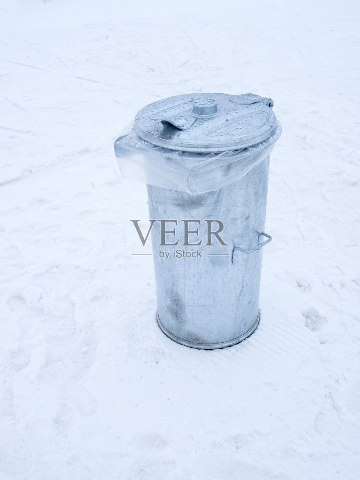 金属垃圾桶因雪融化而盖湿照片摄影图片
