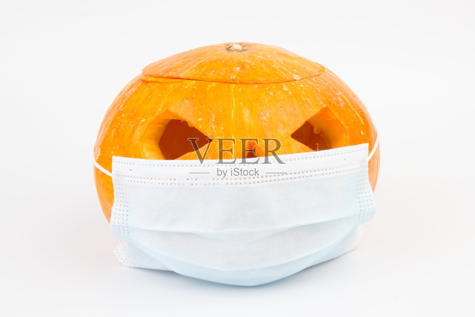 万圣节面具是一个南瓜灯，南瓜戴着医用面具，象征着疾病控制和病毒感染，以及冠状病毒或新冠病毒的安全照片摄影图片