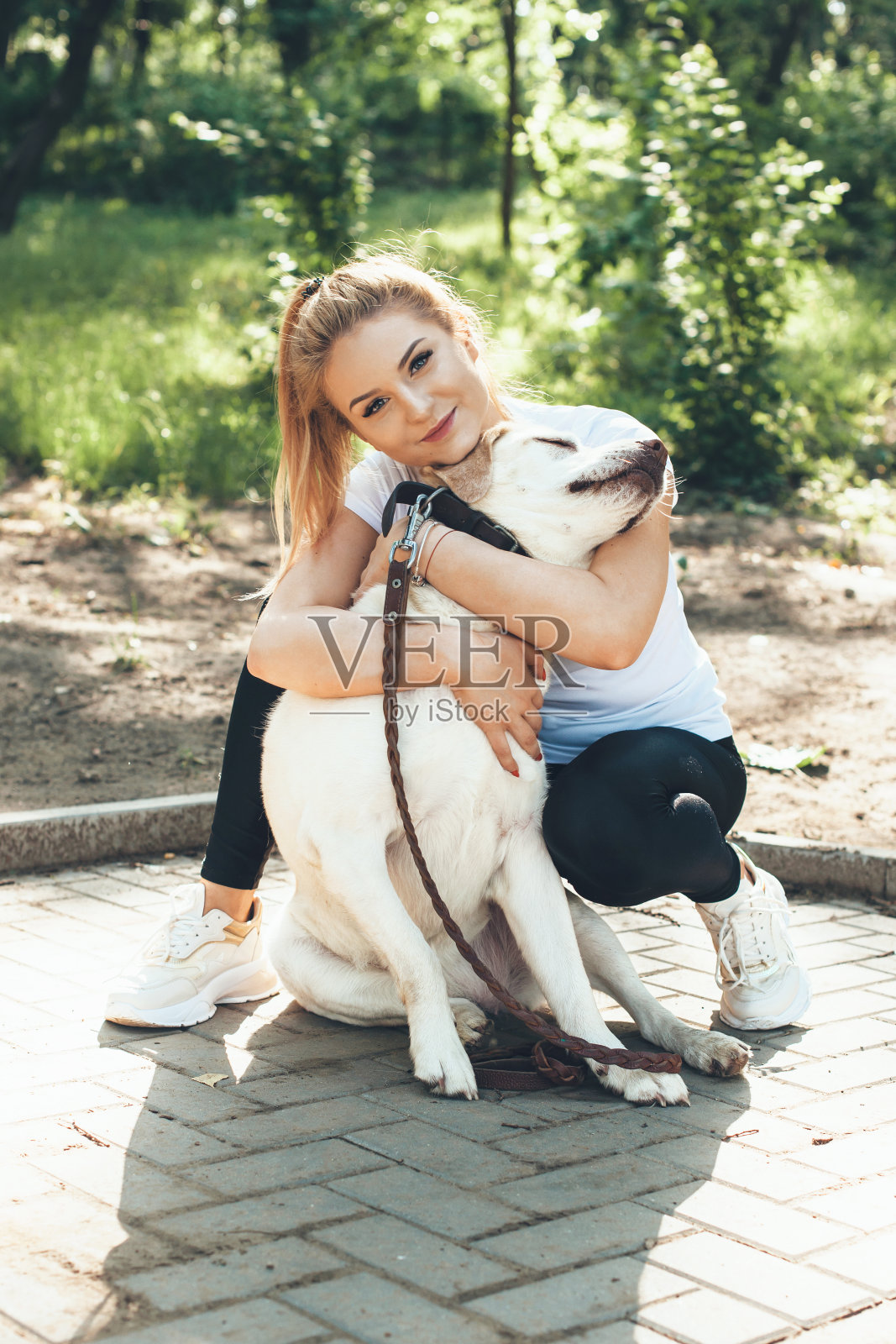 这是一只金毛猎犬和它的主人在公园里看着镜头拥抱在一起的可爱照片照片摄影图片