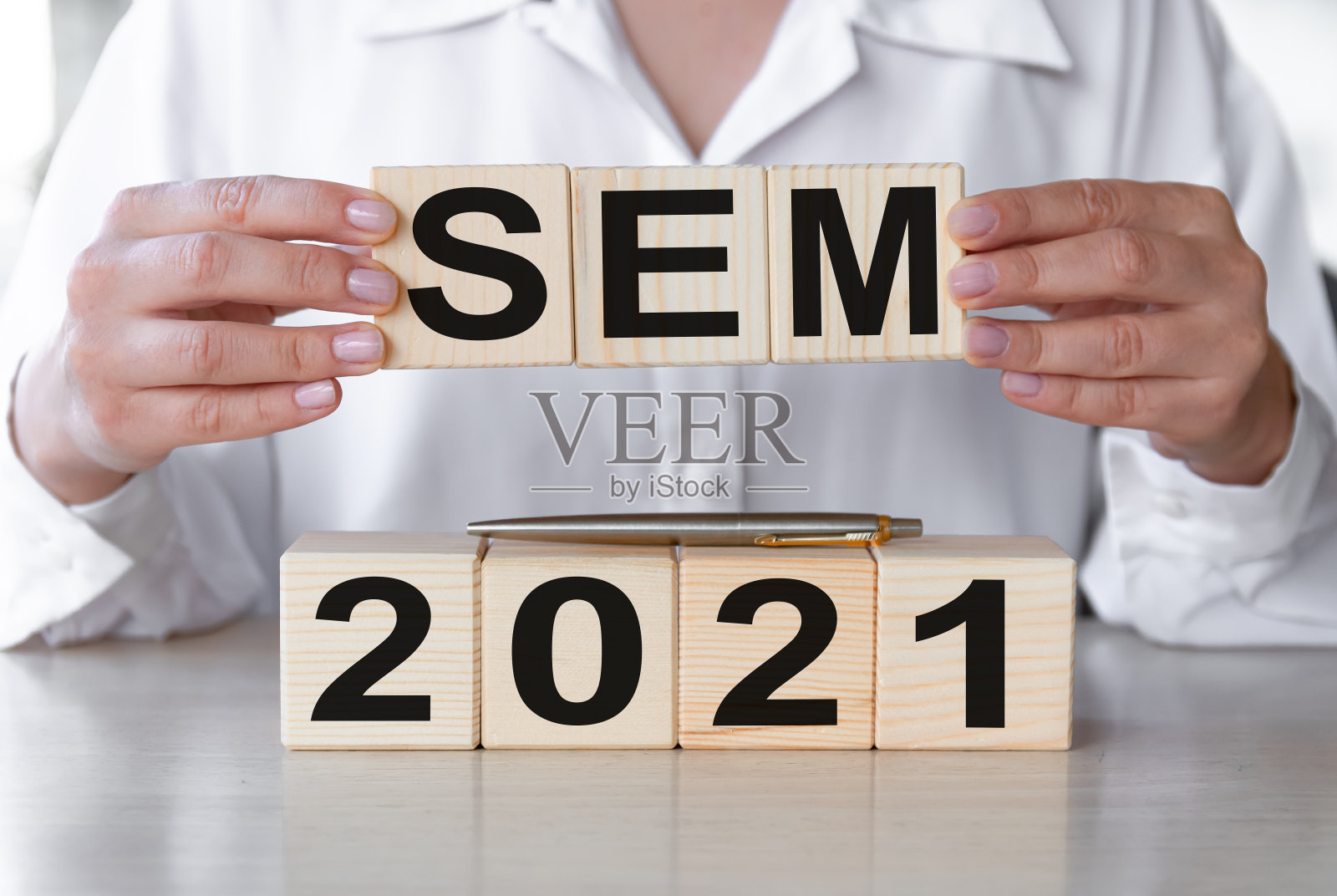 SEM 2021 -木制立方体在木桌上的文本。以女商人之手为背景。商业金融的概念。照片摄影图片