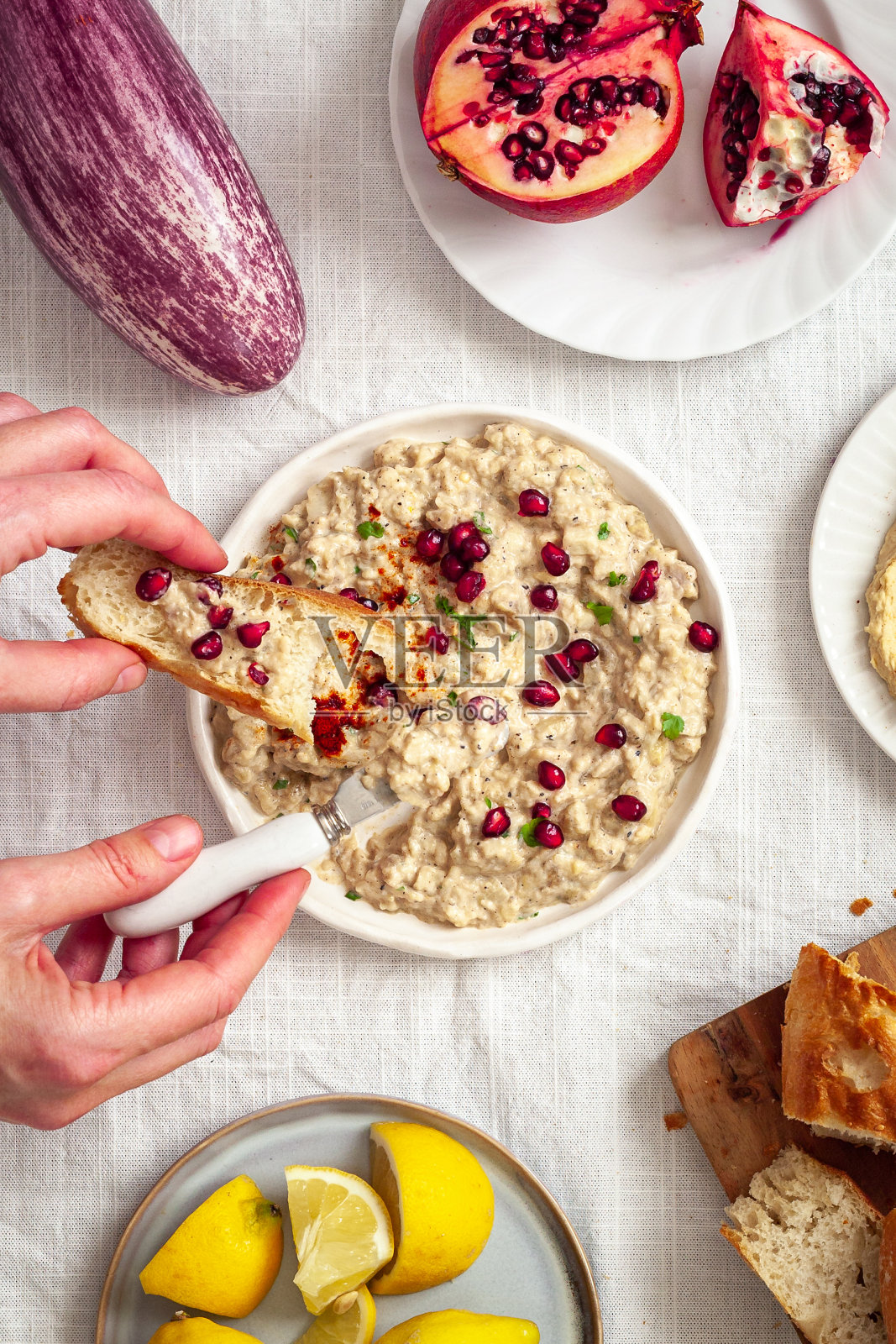 中间有蘸酱的餐桌，一个人拿着一片面包照片摄影图片