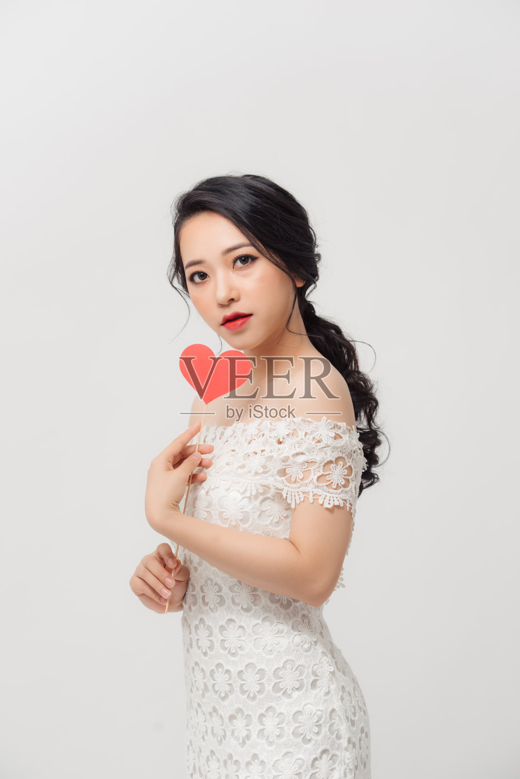 优雅的亚洲女人拿着纸心，孤立地站在白色的背景。照片摄影图片