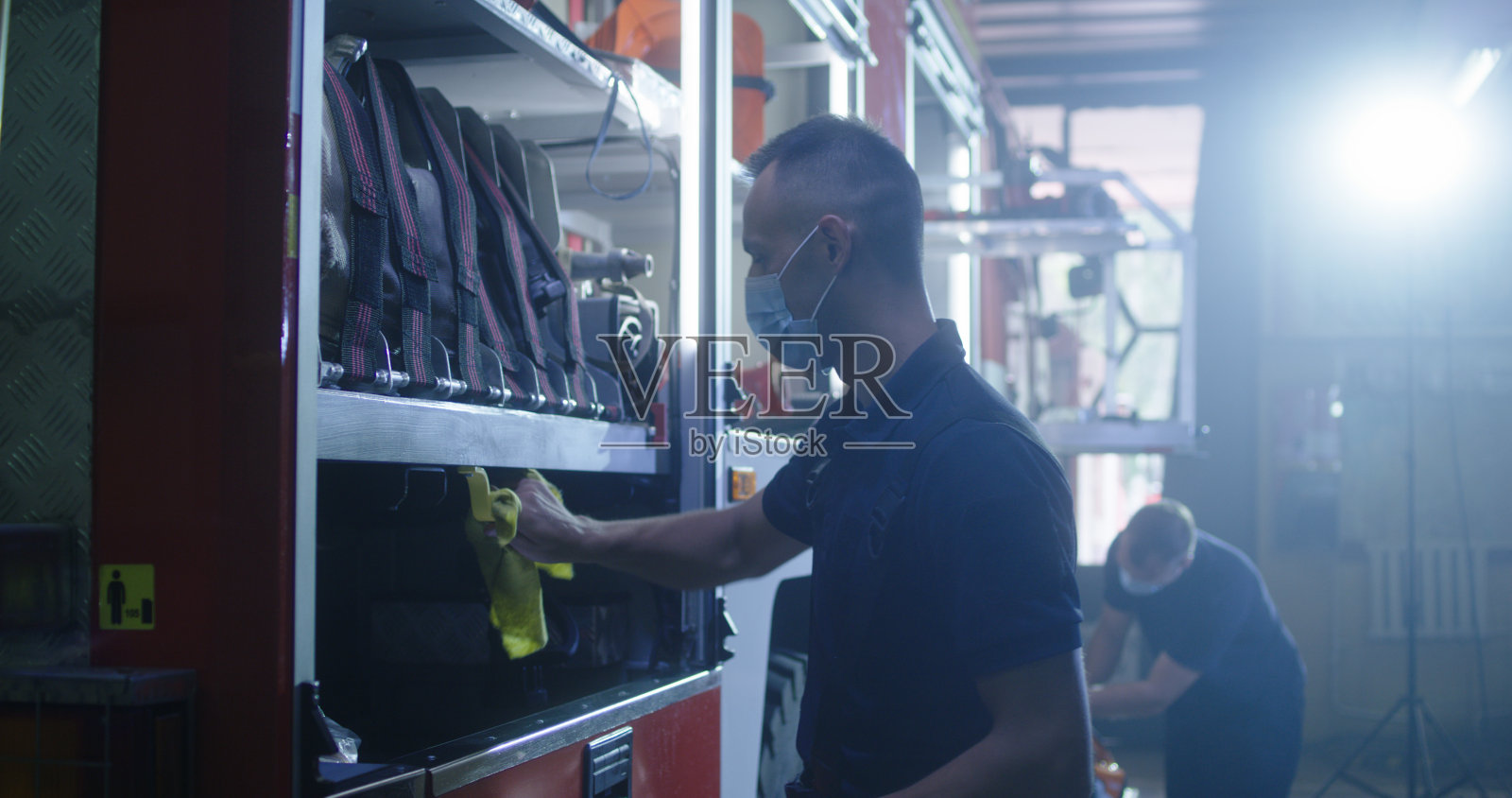 戴口罩清洗消防车的消防员照片摄影图片